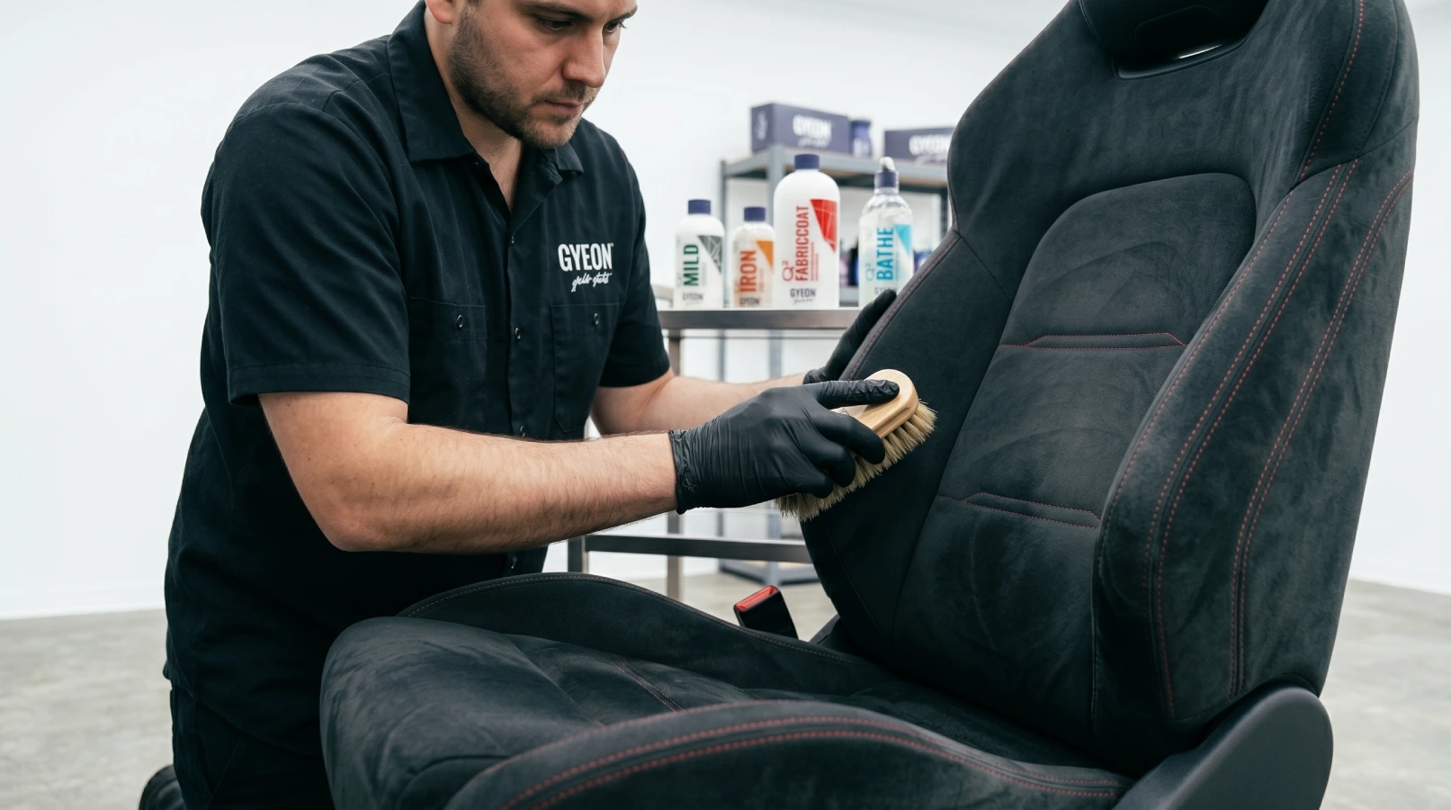 Gyeon tehničar četkicom od prirodne dlake čisti crno alcantara sedište u LaserWash detailing centru Rumenka